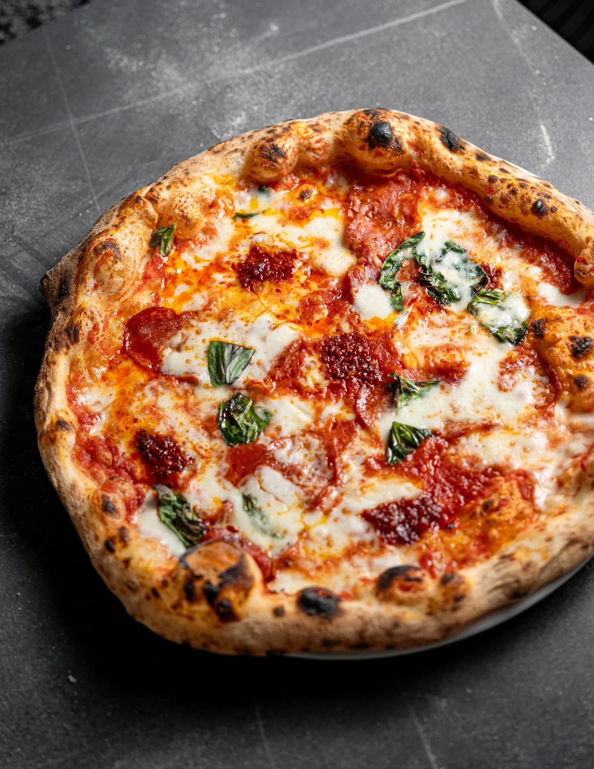 Diavola con salame piccante, 'nduja e basilico su pietra nera